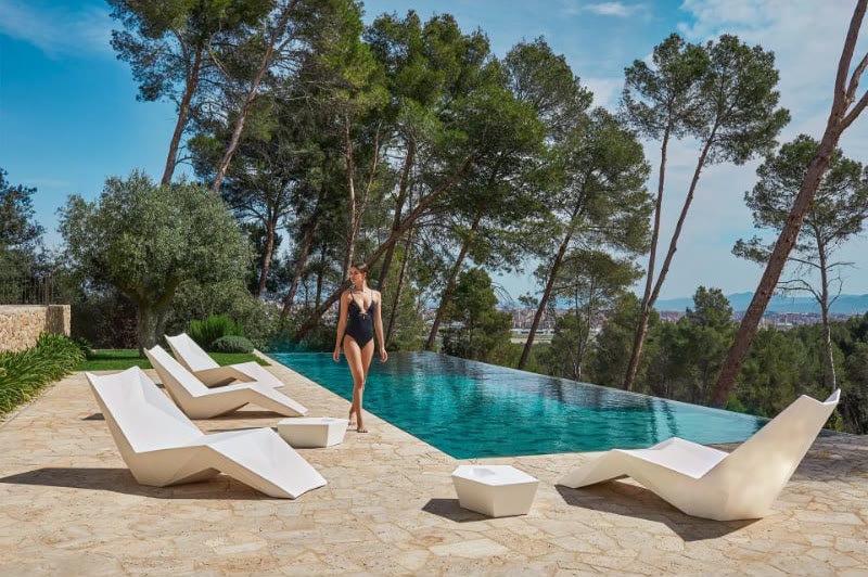 Bains de soleil FAZ de VONDOM autour d'une piscine à débordement sous les pins