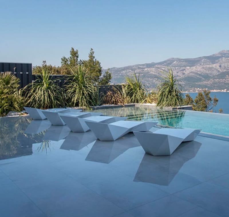 Chaises longues FAZ de VONDOM au bord d'une piscine face à la mer