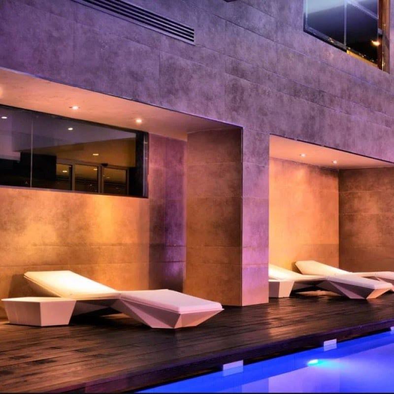 Chaises longues FAZ de VONDOM lumineuses au bord d'une piscine la nuit