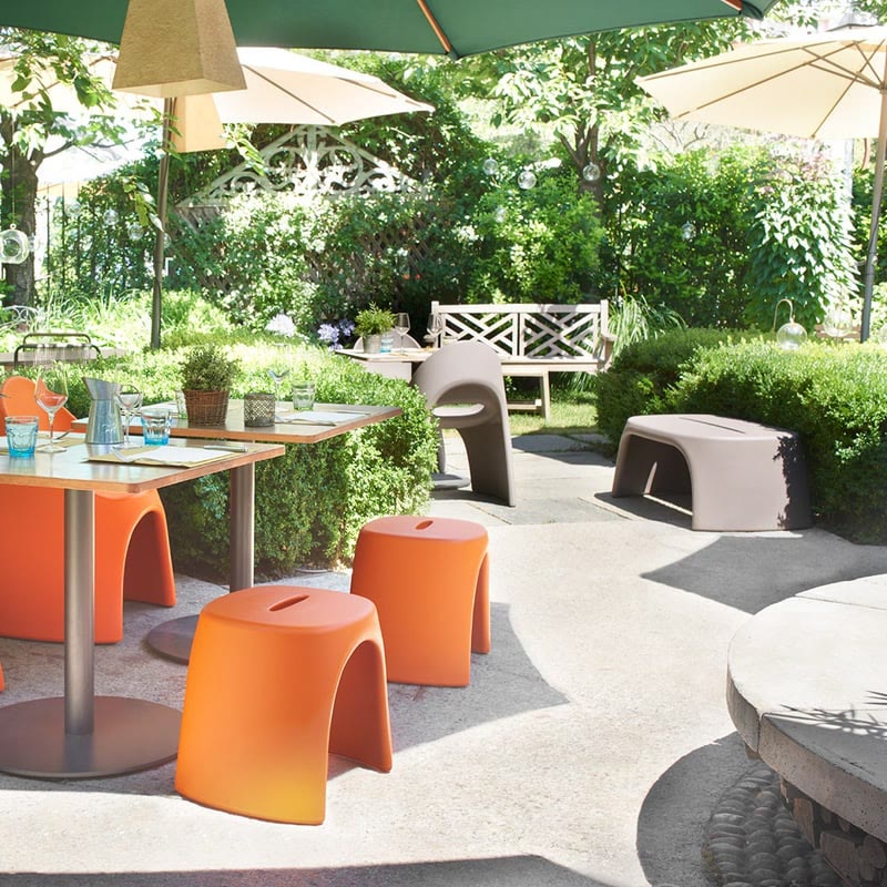 Bancs et tabourets AMELIE de SLIDE orange sur une terrasse de café